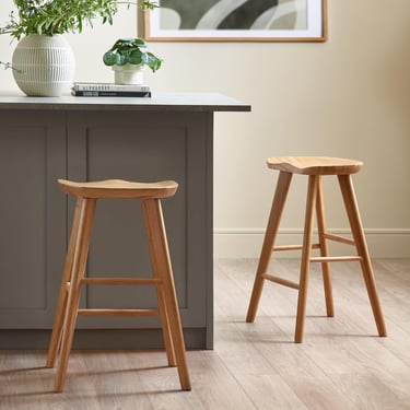 a kitchen counter with a wooden stool and a potted plant
