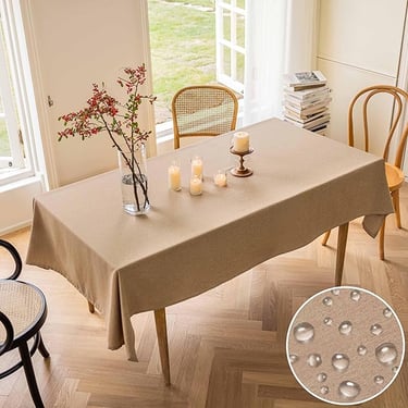 Elegant tan waterproof tablecloth on a rectangular dining table with candles and flowers.