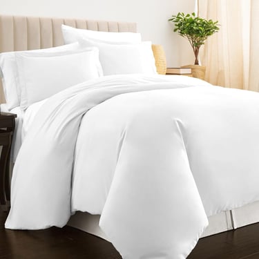 a bed with a white bedding and a plant