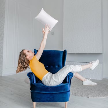 a woman sitting in a chair with a pillow and pillow