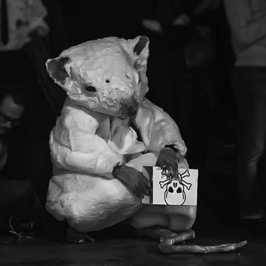 David Noir assis en costume de rat tient une boite avec un dessin de tête de mort | Souris-moi | Photo Bernard Bousquet