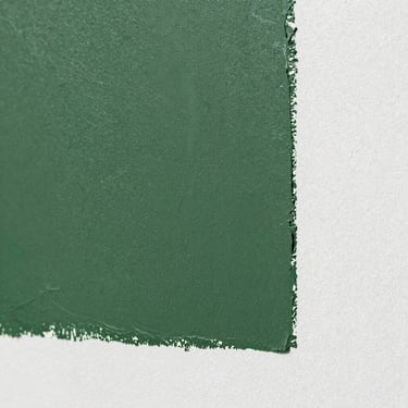 Close-up shot of a matte forest green paint swatch on a smooth plaster wall, crisp texture, bright natural light