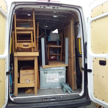 Fourgon de déménagement chargé de meubles en bois, boîtes en carton, objets emballés et caisses métalliques, prêt pour le tra
