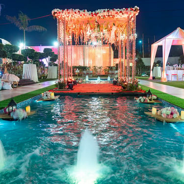 Wedding mandap decor set up over a reflecting pool at dusk