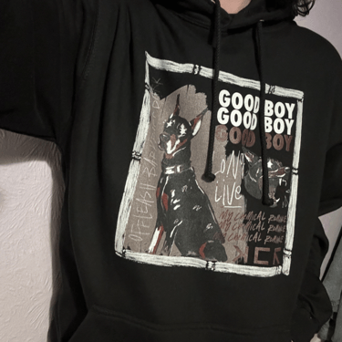 A photo of a person wearing a Good Boy hoodie, the hoodie has an illustration of a doberman dog in two poses.