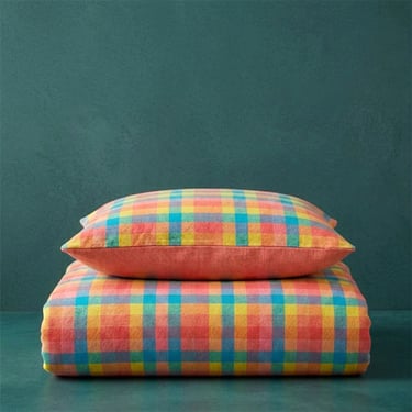 Funda de cojín de rayas de colores sobre fondo turquesa, textil de hogar fotografiado con IA