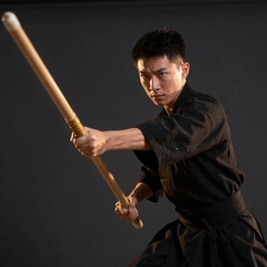 Focused student mid-movement holding a Bo staff, low-angle heroic framing, sharp focus