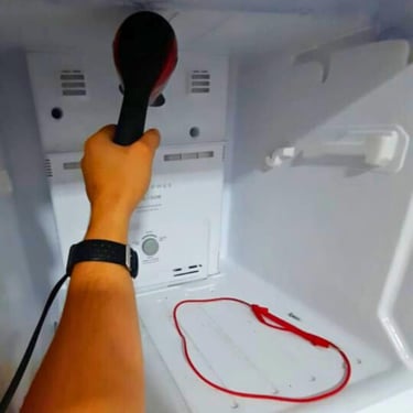 Técnico usando secador para descongelar freezer durante conserto em Curitiba.