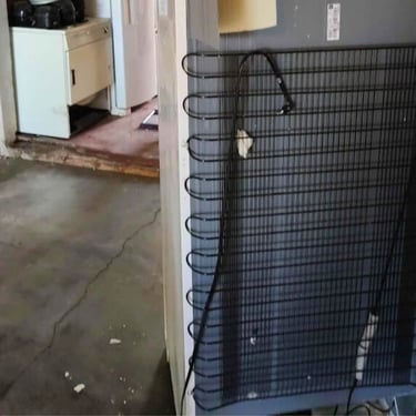 Parte traseira de geladeira com fios e condensador expostos em manutenção em Curitiba.