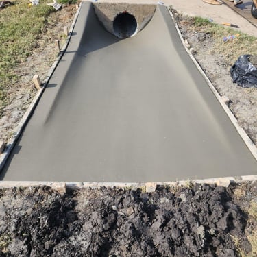 Freshly poured concrete drainage with culvert pipe.