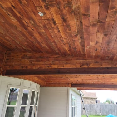 Covered patio with stained wood ceiling and beams.