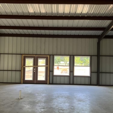 Interior of metal shed with doors and concrete floor.