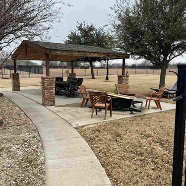 Outdoor pavilion with wood roof and patio furniture.