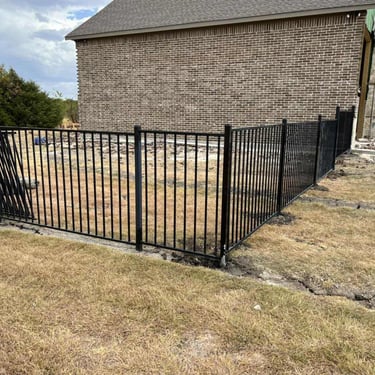 Black metal fence installed beside brick house.