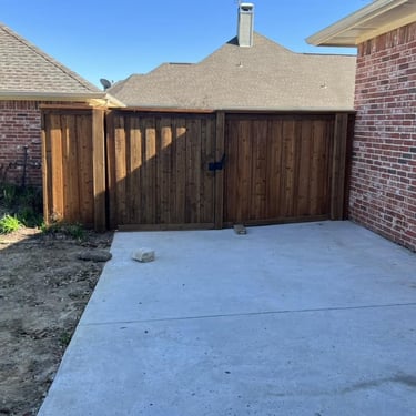 Wooden privacy fence with gate and concrete slab.