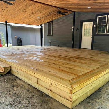 Covered wooden deck with steps and natural wood ceiling.