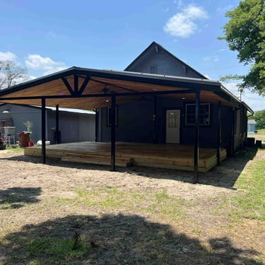 Covered wooden deck with black posts and wood ceiling.