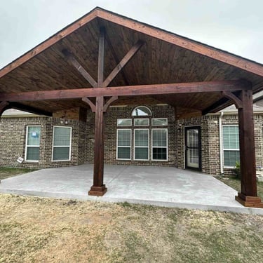 Covered patio with stained wood gable roof and concrete slab.