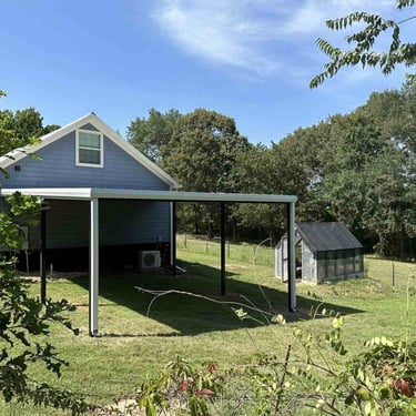 Metal patio cover beside blue house.