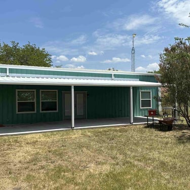 Green metal building with white metal patio cover.
