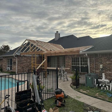 Covered patio under construction with exposed roof framing.