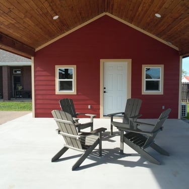 Covered patio with red shed and chairs.