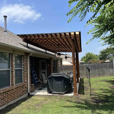 Wood pergola attached to brick house.