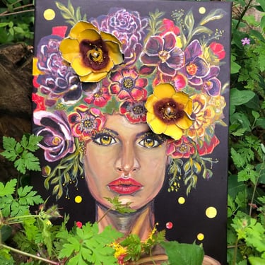 Portrait mixte aux yeux d'or et couronne florale rouge, jaune, violette, avec fleurs 3D, posé dans la verdure.