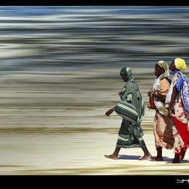 a group of people walking down a beach