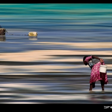 une femme vêtue d'une robe rose marche sur la plage. Photographie exposé  à Marché Création Paris