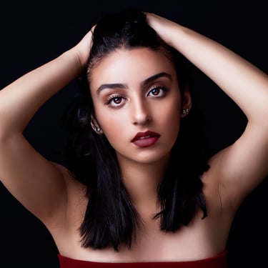 a beautiful brown eyed girl with tanned skin, plump auburn lips, pulling her hair back and posing like a model