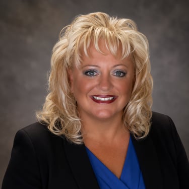 Professional headshot of a JoJo Caruana businesswoman in a black blazer and blue blouse.