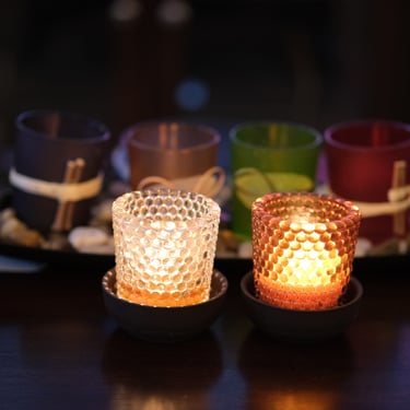 Two lit beeswax votive candles, side by side on a table
