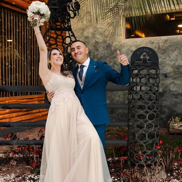 Recién casados celebrando sonriendo a cámara. La novia levanta el ramo y disfrutan de su momento juntos en Quito, Ecuador