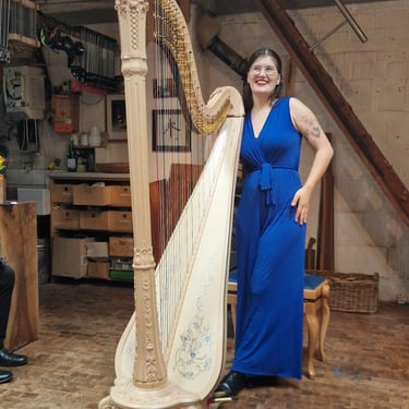 Clara Busemann steht an ihrer harfe und schaut lächelnd nach oben