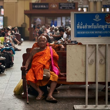 Un moine assis sur un banc dans une gare