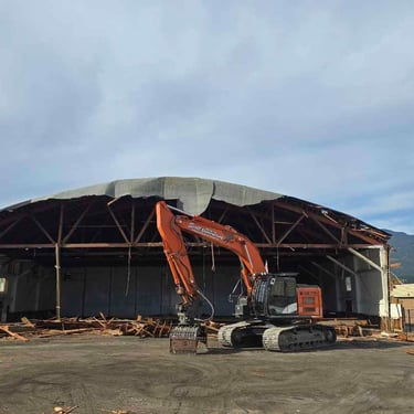excavator in front of an demolition project of an arena