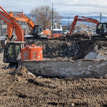 Three excavators digging out a concrete foundation