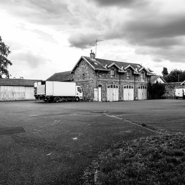 Cour goudronnée avec vieux bâtiments et un amion