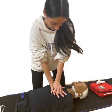 a woman performing chest compressions on an adult trainig manikin