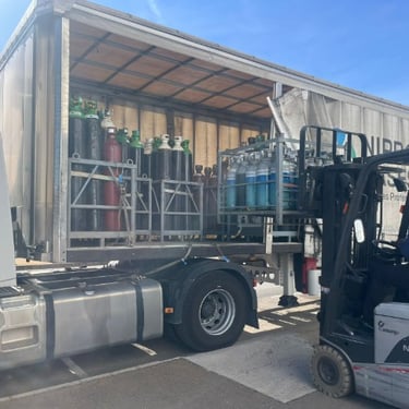 Foto de maniobra de descarga de botellas de gas en jaulas desde trailer