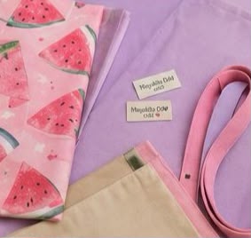 ela hecha a mano con estampado de sandía rosa y artículos de costura, junto con etiquetas de ropa.