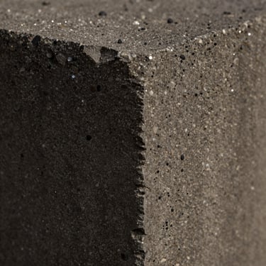 Macro close-up of deep charcoal concrete texture, exposed basalt aggregate, subtle crystalline sparkles, moody shadows.