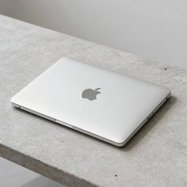 A clean silver MacBook Air M2 closed on a minimalist concrete table