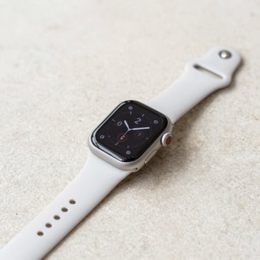 Apple Watch Series 9 with a sport band resting on a neutral stone surface