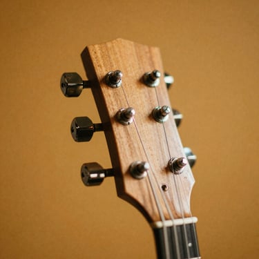 Close-up of guitar headstock tuning pegs against a warm amber background, shallow depth of field, film stock color grading, grain texture