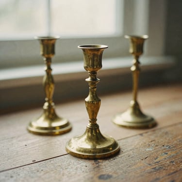 Weathered brass candlesticks showing natural patina on a rustic wooden surface, soft diffused daylight, warm tones, 35mm film