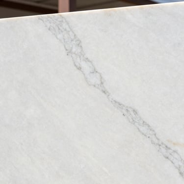 Close-up of a premium white marble slab with subtle grey veins, polished texture, soft natural lighting