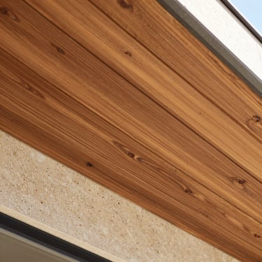 Installed WPC composite wood cladding on an outdoor ceiling, warm brown tones, linear architectural shadows