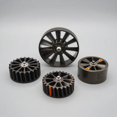 Five different sized fan stators, from 5 Sut to 1 Ten, arranged neatly on a clean gray surface, high-contrast industrial studio lighting